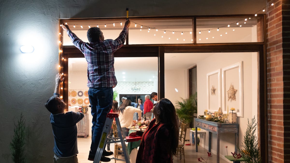 Family decorating the house for Christmas and hanging lights