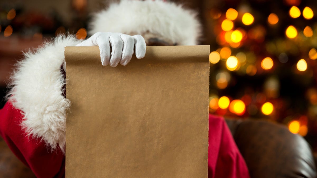 Santa Claus reading a wish list at home.