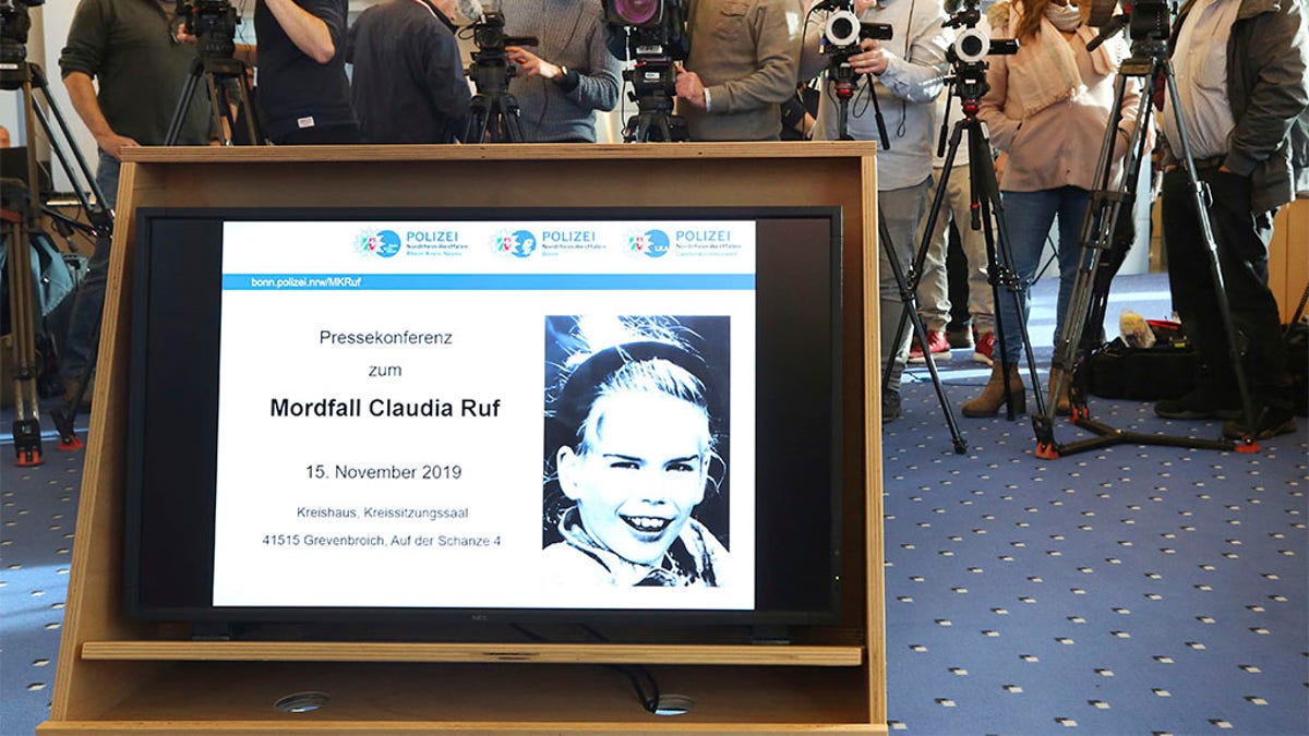 In this Friday, Nov. 15, 2019 photo a picture of Claudia Ruf is seen on a video screen as jounalists wait for the start of a press conference in Grevenbroich, Germany. Police in the western German city of Grevenbroich have asked about 900 men to come forward and have their DNA tested to help solve the gruesome killing of an 11-year-old girl decades ago. The girl, Claudia Ruf, was kidnapped, raped and choked to death by an anonymous murderer in 1996. (Roland Weihrauch/dpa via AP)