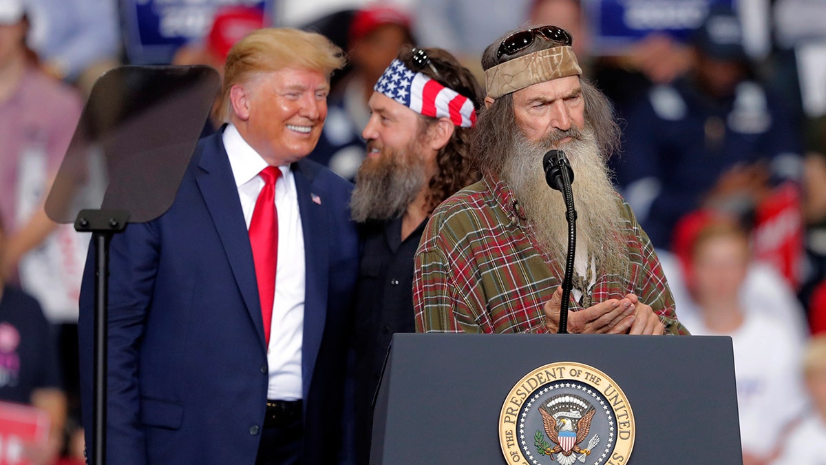 President Donald laughs with Willie Robertson, of the reality TV series Duck Dynasty, and Phil Roberston, the family patriarch, right, at a campaign rally in Monroe, La., Wednesday, Nov. 6, 2019.
