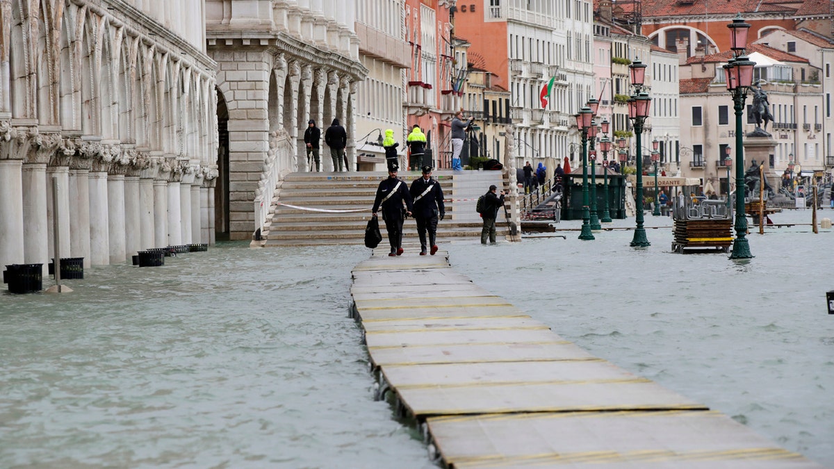 Two police officers walk on a gangway in flooded Venice, Italy, Sunday, Nov. 17, 2019.