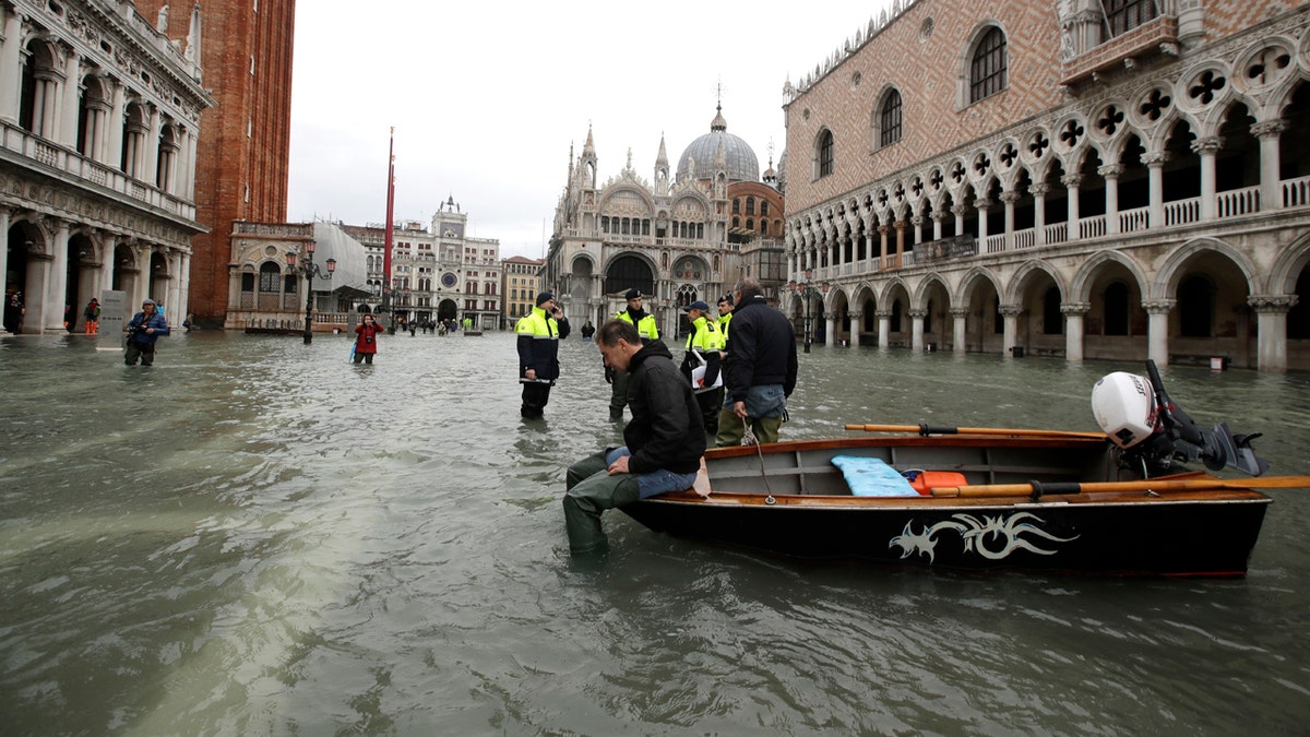 A man sits on a small boat in a flooded St.Mark square in Venice, Italy on Sunday.