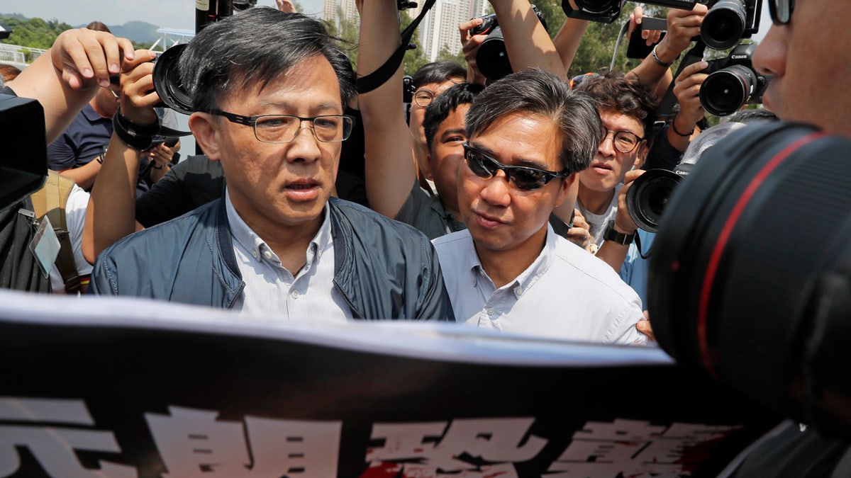 In this Aug. 12, 2019, photo, pro-Beijing lawmaker Junius Ho, left, attends a demonstration of an anti-riot vehicle equipped with water cannon at the Police Tactical Unit Headquarters in Hong Kong.