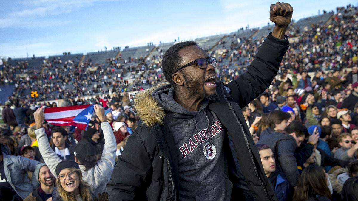 In this Saturday, Nov. 23, 2019, photo, Harvard and Yale students protest during halftime of the NCAA college football game between Harvard and Yale at the Yale Bowl in New Haven, Conn. Officials say 42 people were charged with disorderly conduct after the protest interrupted the game. (Nic Antaya/The Boston Globe via AP)
