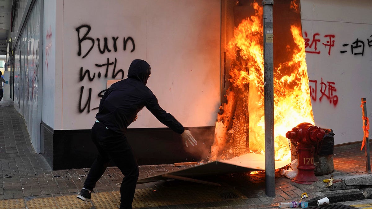 A protester sets fire to the cardboards outside the Bank of China branch during a protests in the Central district of Hong Kong, Monday, Nov. 11, 2019.