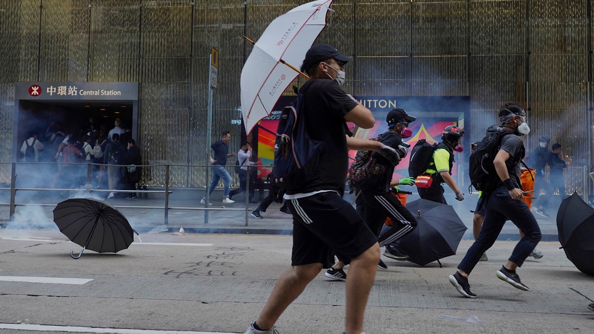 Pro-democracy protesters and people run away from tear gas fired by riot police during a rally in Central in Hong Kong, Tuesday, Nov. 12, 2019.