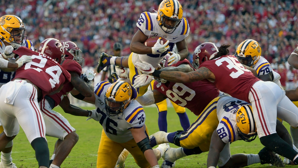 LSU running back Clyde Edwards-Helaire (22) dives over Alabama's Raekwon Davis (99) and Markail Benton (36) to score a touchdown in the first half of an NCAA college football game, Saturday, Nov. 9, 2019, in Tuscaloosa, Ala. (AP Photo/Vasha Hunt)