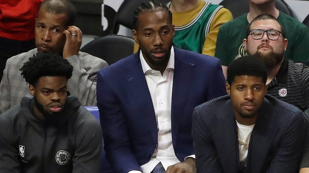 Los Angeles Clippers' Kawhi Leonard, center, and Paul George, right, watch from the bench during the second half of the team's NBA basketball game against the Milwaukee Bucks on Wednesday, Nov. 6, 2019, in Los Angeles. (AP Photo/Marcio Jose Sanchez)