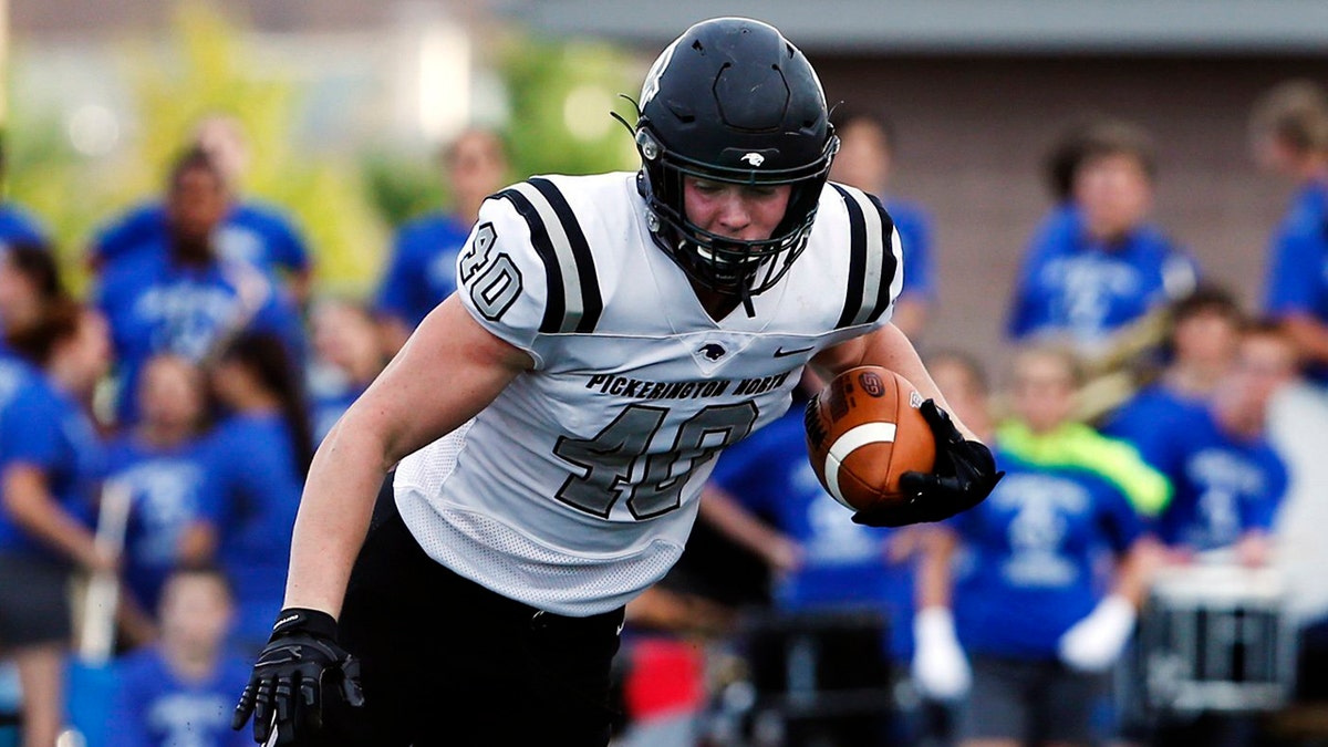 In this Aug. 30, 2019 photo, Pickerington North's Jack Sawyer (40) tries to break free of Olentangy Liberty's Andrew Barrett during the first quarter of a high school football game in Lewis Center, Ohio. As college football teams across the South benefit from deep talent pools in their backyards, in the Midwest and Northeast the selection is getting thinner, especially when it comes to blue chip recruits. (Eric Albrecht/The Columbus Dispatch via AP)