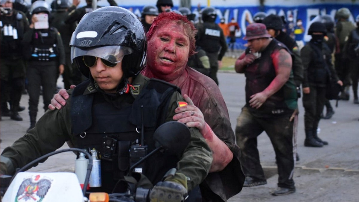 Police rescue Vinto mayor Patricia Arce Guzman on a motorcycle after people threw paint and dirt on her following a fire in Vinto's Town Hall, Quillacollo, Bolivia, November 6, 2019.