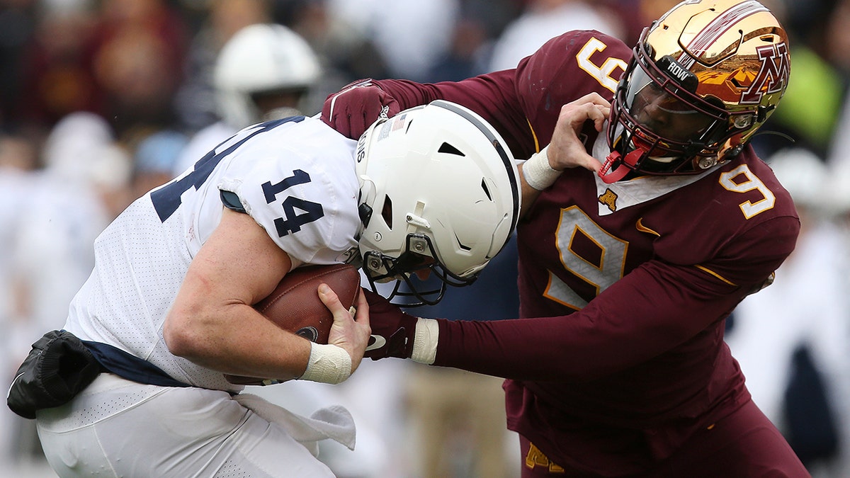 Minnesota defensive lineman Esezi Otomewo (9) grabs Penn State quarterback Sean Clifford (14) during an NCAA college football game Saturday, Nov. 9, 2019, in Minneapolis. Minnesota won 31-26. (AP Photo/Stacy Bengs)