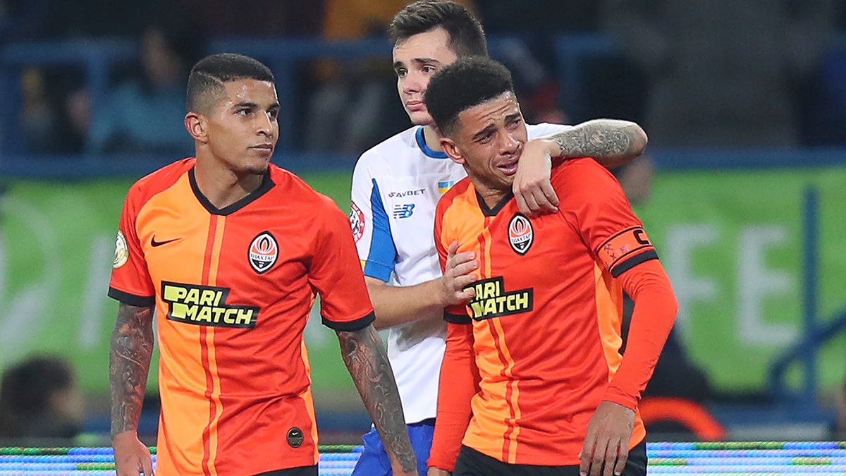 Shakhtar's Brazilian player Taison, right, reacts as he leaves the pitch after he was red-carded for his reaction on racial abuse, while Dynamo Kyiv Mykola Shaparenko, center, calmed him down, during Premier League soccer match in Kharkiv, Ukraine, on Sunday, Nov. 10, 2019. Shakhtar's Dodo, left, looks on. The Ukrainian Premier League on Monday called for an inquiry after a Brazilian player for Shakhtar Donetsk was sent off for responding to racist abuse with an obscene gesture. (AP Photo/Oleksandr Osipov)