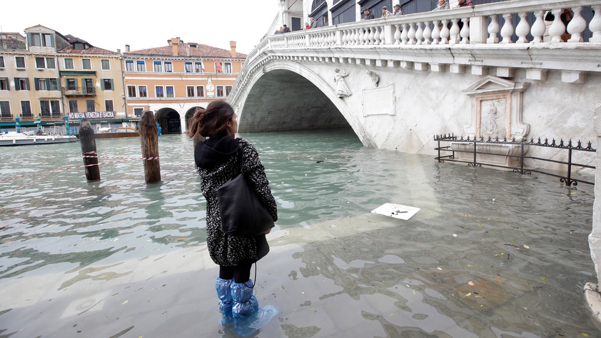 A woman looks at the Rialto Bridge during high water, in Venice, Wednesday, Nov. 13, 2019.