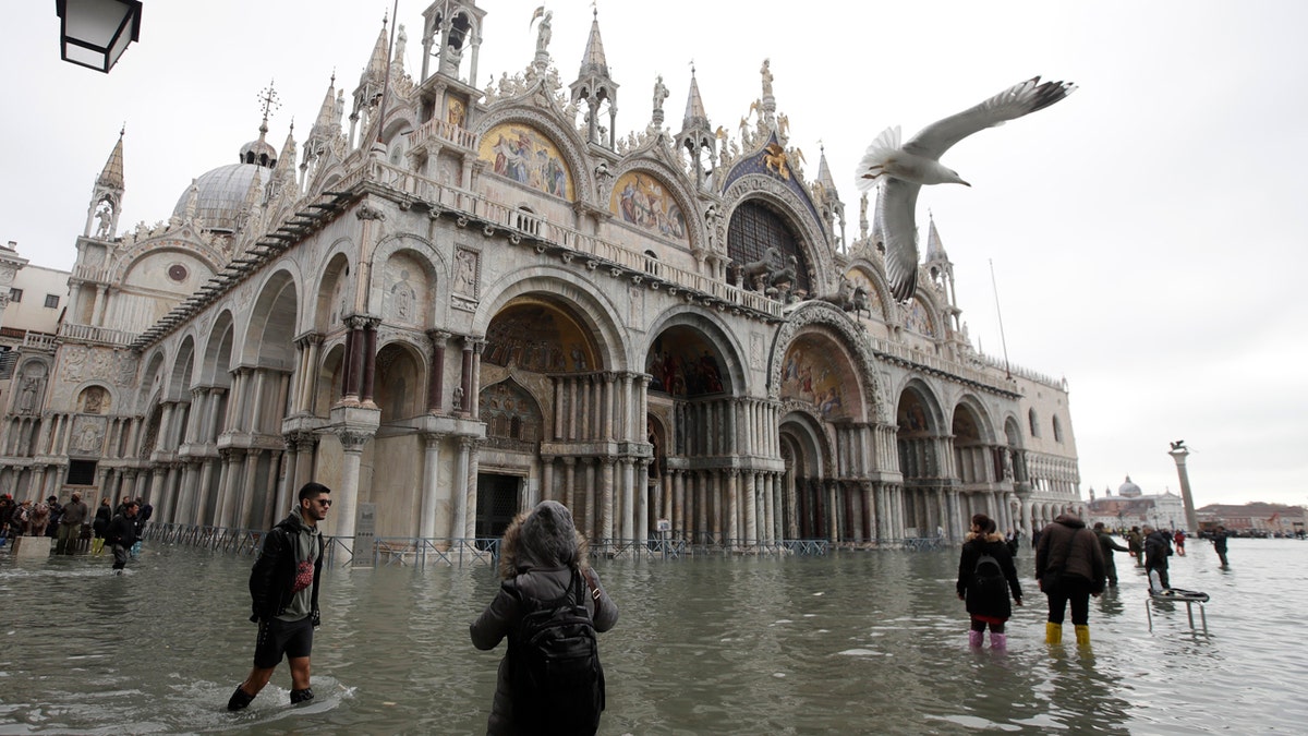 People wade in high water, in Venice, Wednesday, Nov. 13, 2019.