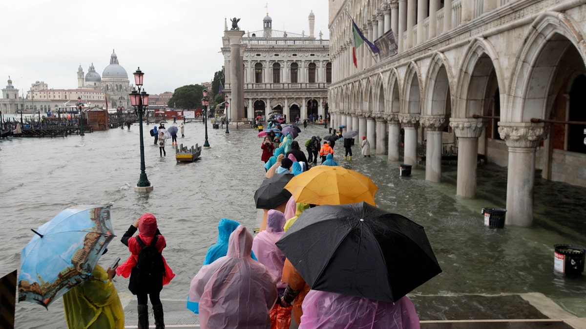 People walk on catwalk set up on the occasion of a high tide, in a flooded Venice, Italy, Tuesday, Nov. 12, 2019.