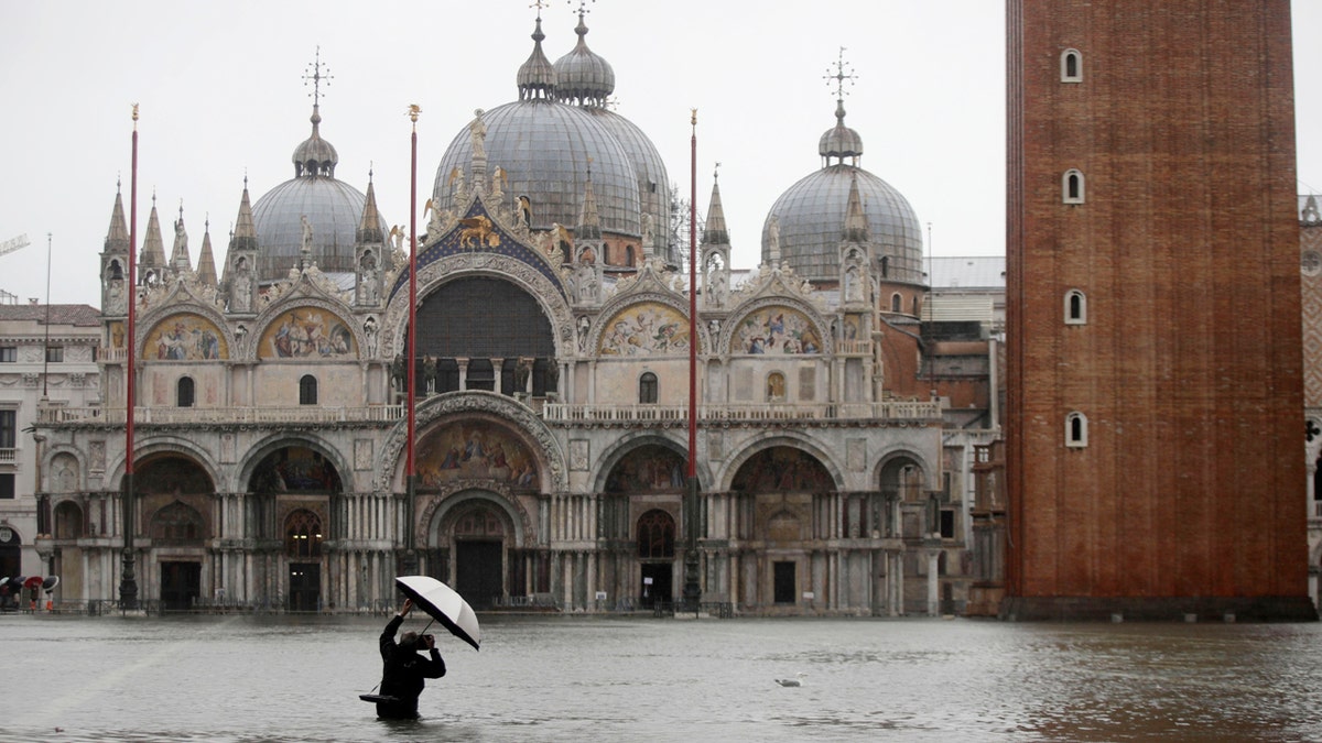 A photographer takes pictures in a flooded St. Mark's Square, in Venice, Italy, Tuesday, Nov. 12, 2019.