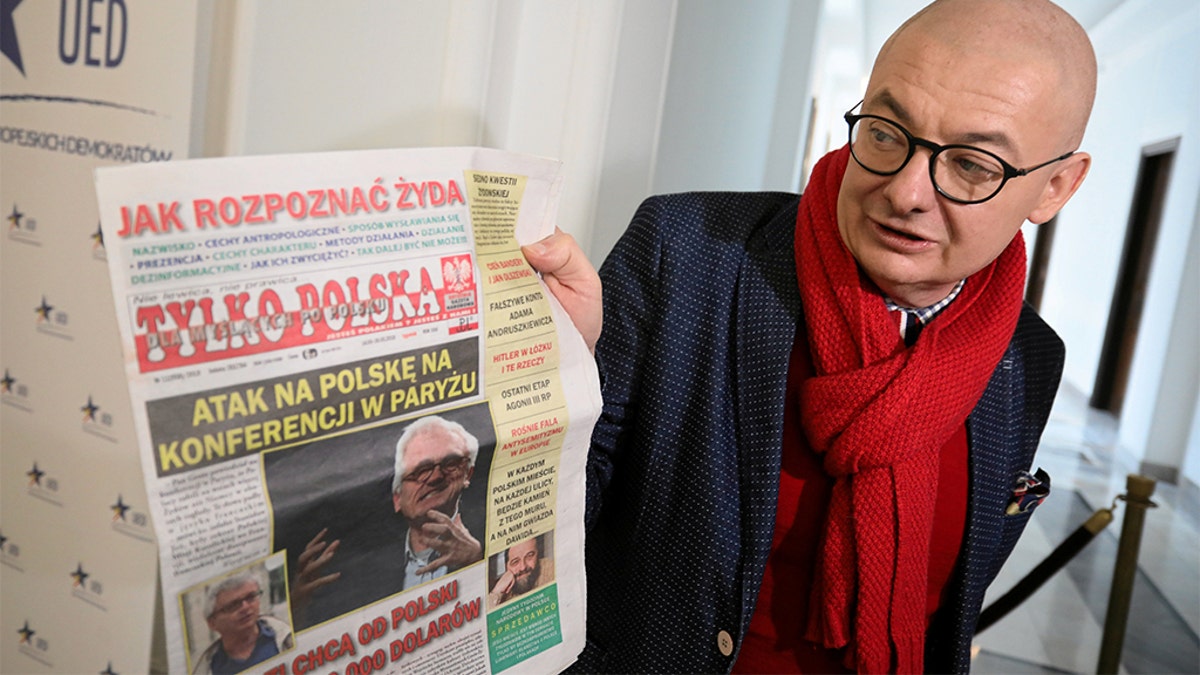 Polish MP Michal Kaminski poses as he displays a front page of Tylko Polska newspaper with headline "How to Spot a Jew" in Warsaw, Poland March 13, 2019. 