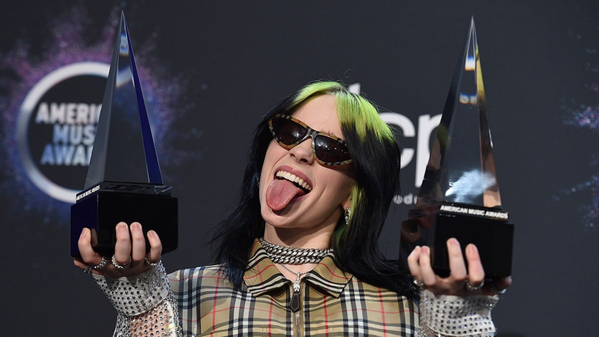 Billie Eilish poses in the press room with the award for new artist of the year and favorite alternative rock artist at the American Music Awards on Sunday, Nov. 24, 2019, at the Microsoft Theater in Los Angeles. (Associated Press)