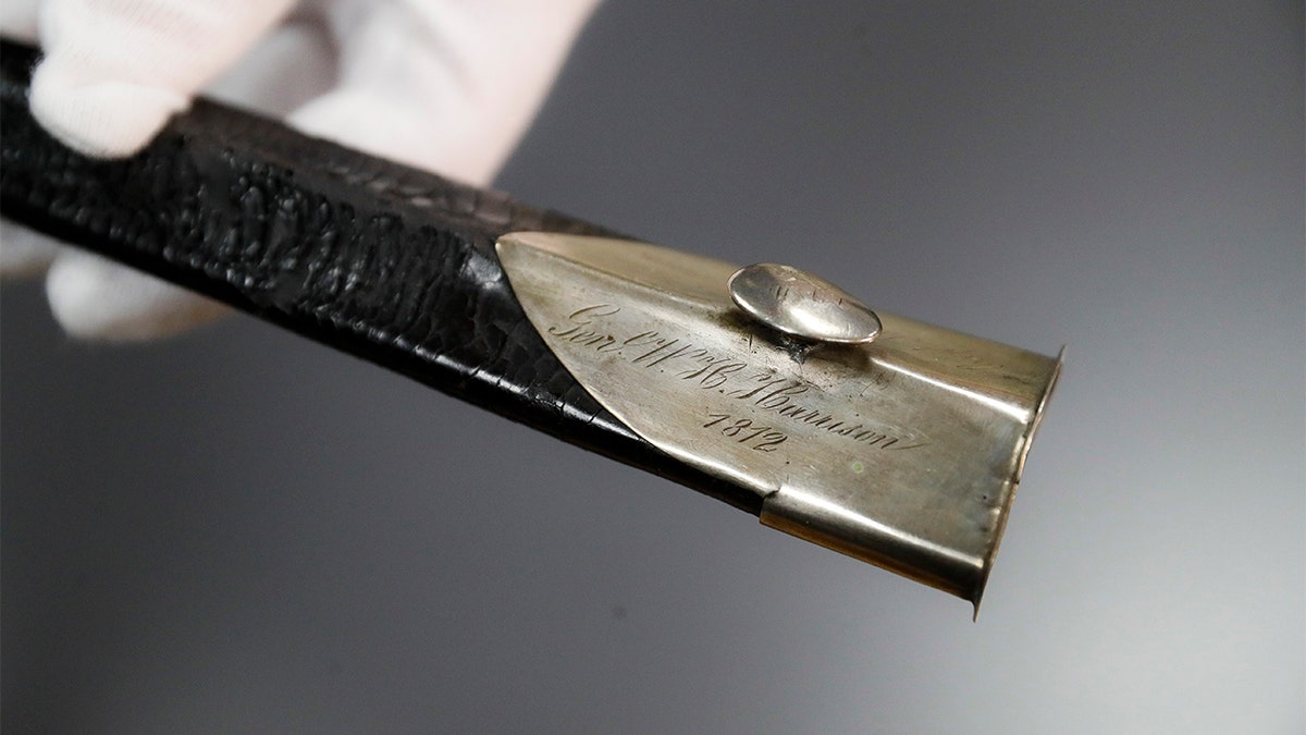 Hamilton County Sheriff Jim Neil points out the engraving 'Gen. W. H. Harrison' on the scabbard of the sword Wednesday. (AP Photo/John Minchillo)