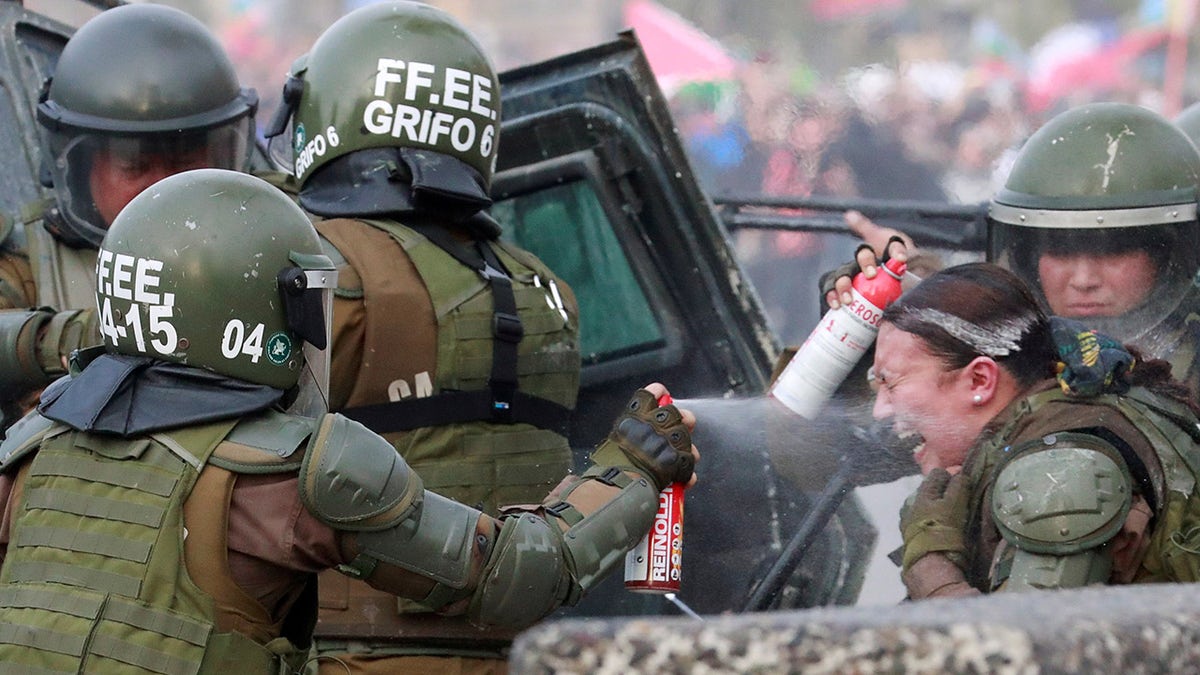 A riot police officer that was on fire is assisted by colleagues during a protest against Chile's government in Santiago, Chile, Nov. 4.