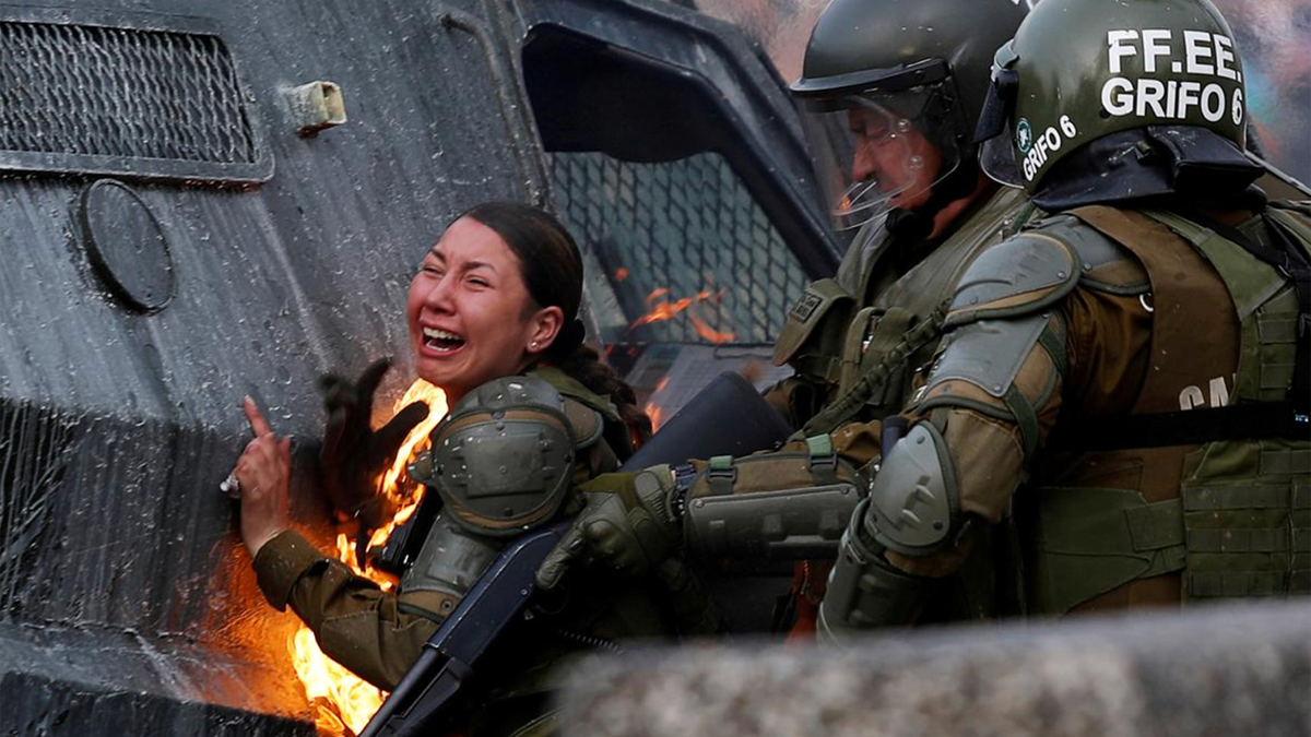 A riot police officer on fire reacts during a protest against Chile's government in Santiago, Chile