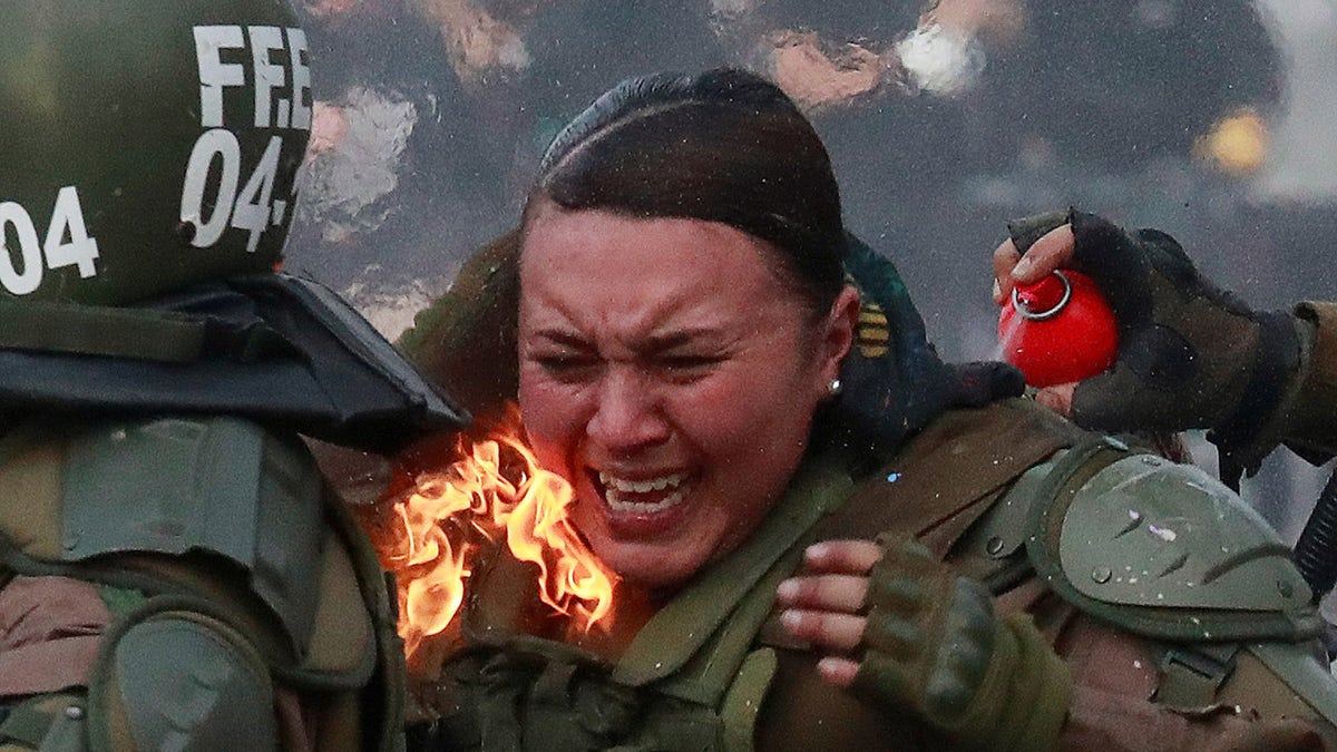 A riot police officer on fire is assisted by colleagues during a protest against Chile's government in Santiago, Chile, Nov. 4, 2019.