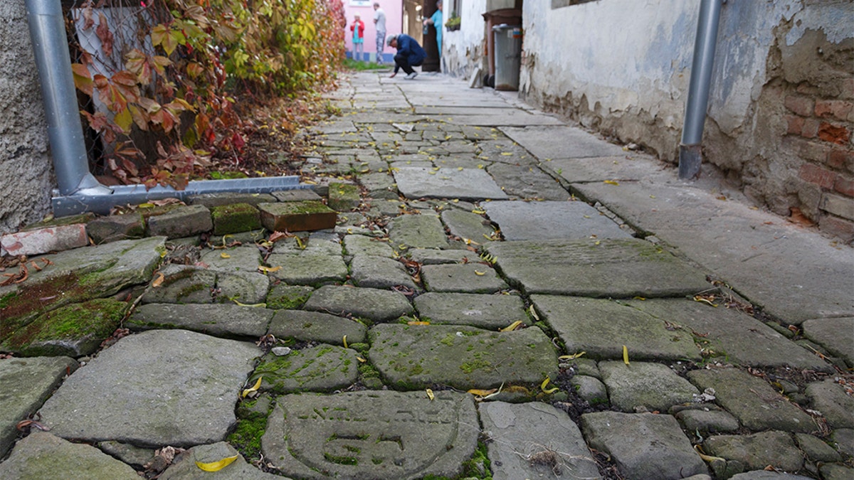 In this picture taken on Monday Oct. 26, 2015, Tomas Jelinek looks at pavement made of tombstones in efforts to restore a former Jewish cemetery in Prostejov, Czech Republic.