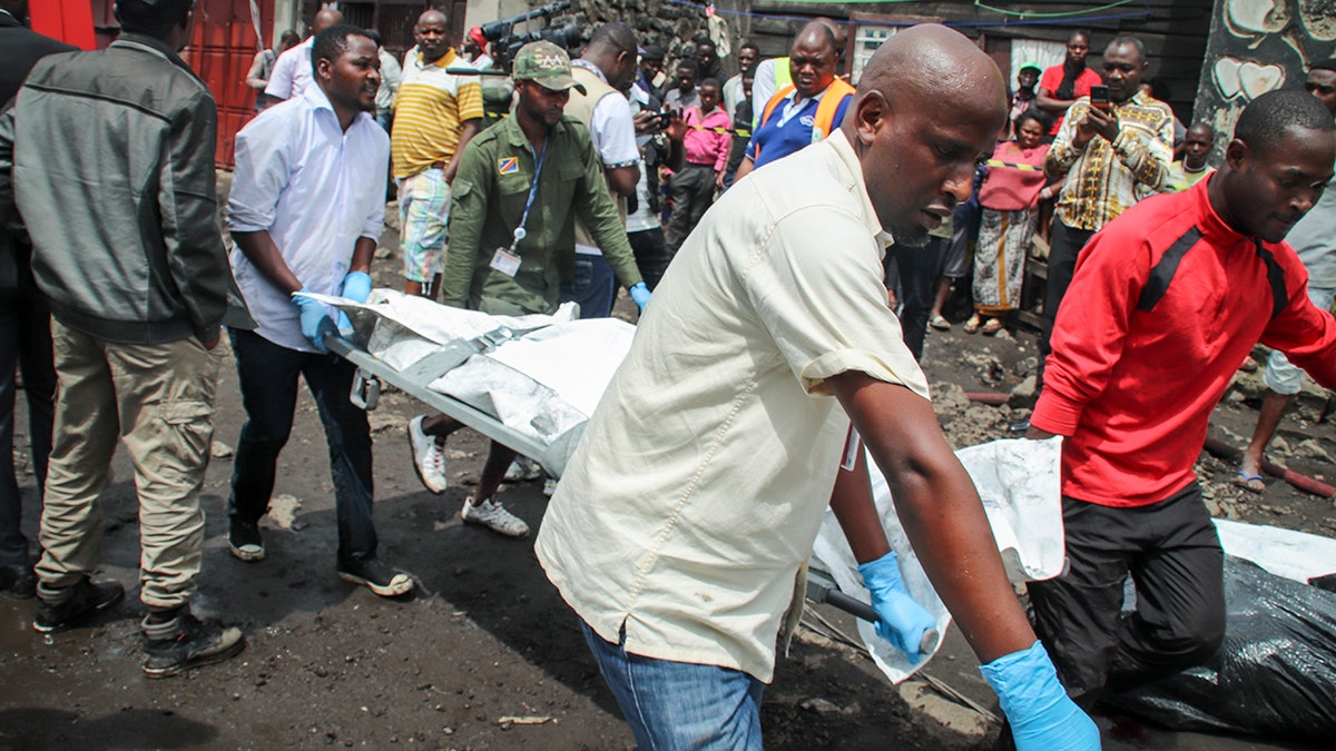 Rescuers remove bodies from the debris of an aircraft that crashed into two residential homes. (AP Photo/Justin Kabumba)