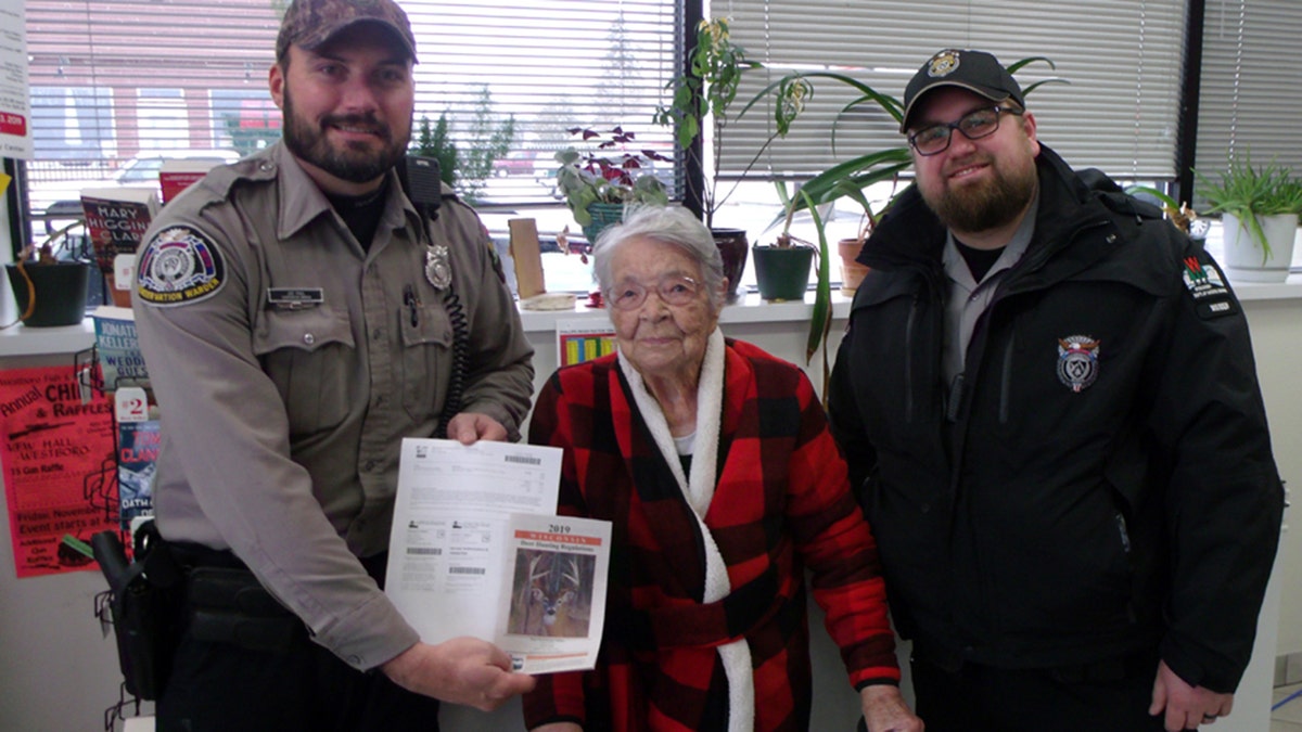 Florence poses with DNR Wardens after purchasing her first gun deer license.