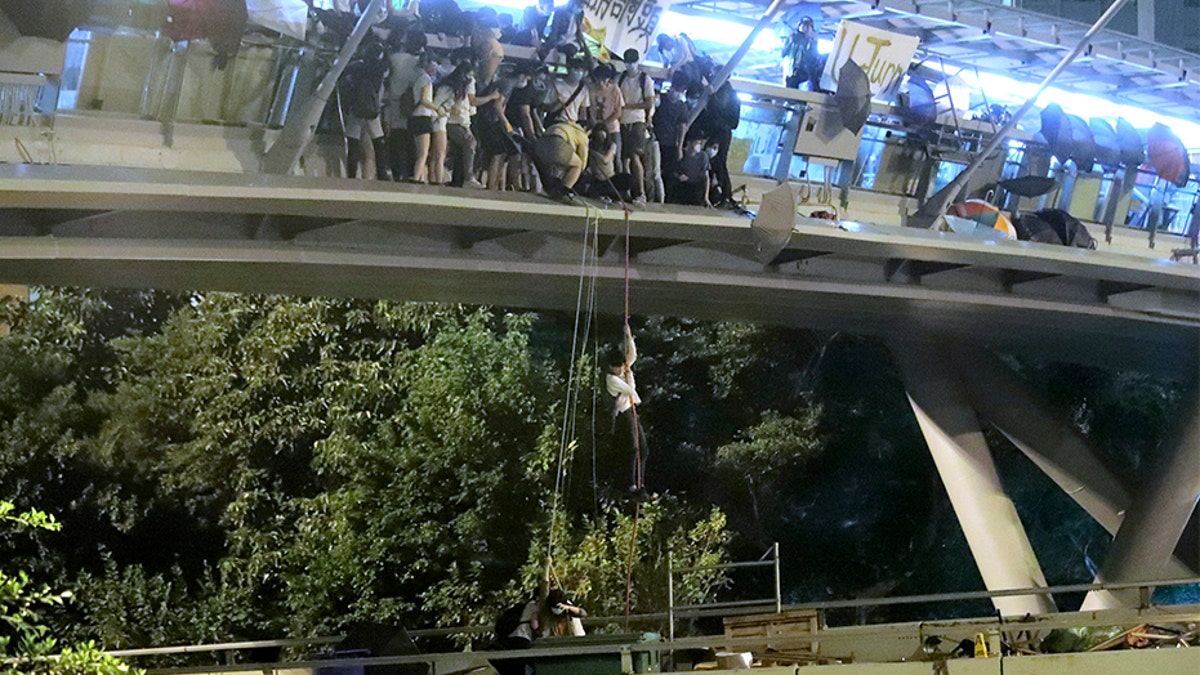Protestors use a rope to lower themselves from a pedestrian bridge to waiting motorbikes in order to escape from Hong Kong Polytechnic University late Monday. (AP)