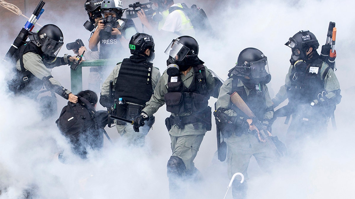 Police in riot gear move through a cloud of smoke as they detain a protester at the Hong Kong Polytechnic University in Hong Kong, on Monday.