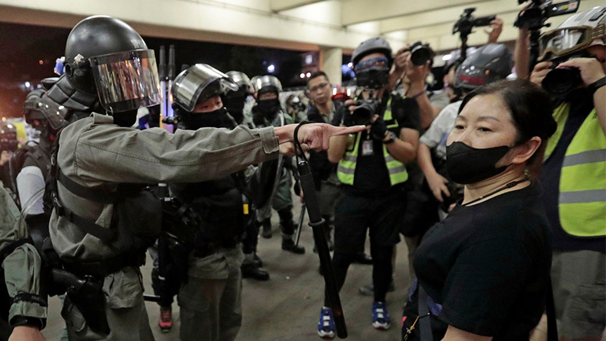 Police in riot gear ask a woman to take off her mask outside a train station in Hong Kong, on Nov. 3. (AP)