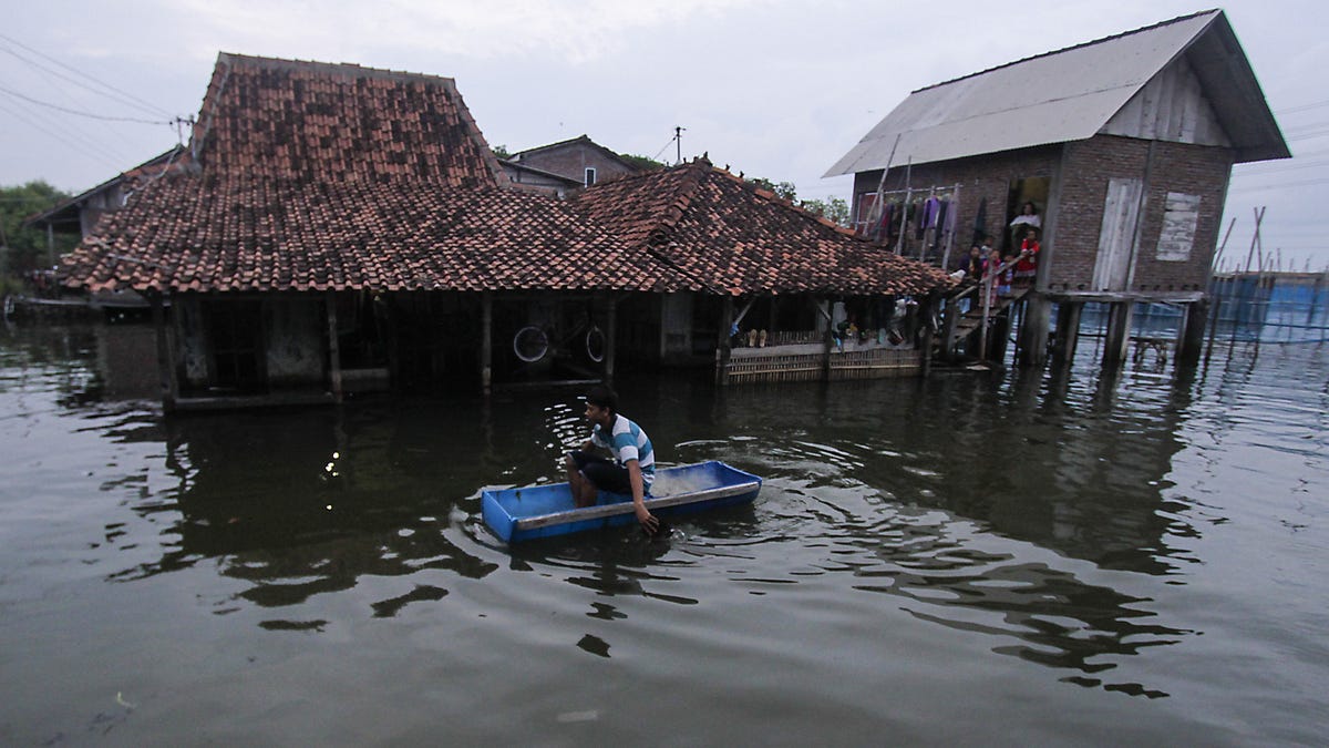 DEMAK, INDONESIA FEBRUARY 2: A man uses a handmade boat to reach his water-logged home in Sriwulan village, Sayung sub-district of Demak regency, Central Java, Indonesia on February 2, 2018.