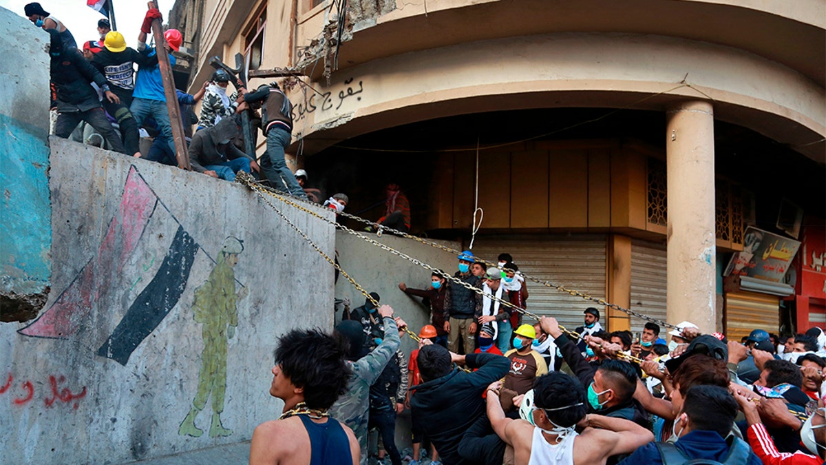 Demonstrators trying to pull down concrete walls placed by Iraqi security forces to close in the historic Rasheed Street in Baghdad on Sunday.