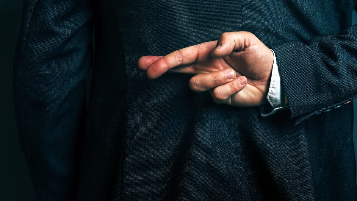 Lying businessman holding fingers crossed behind his back