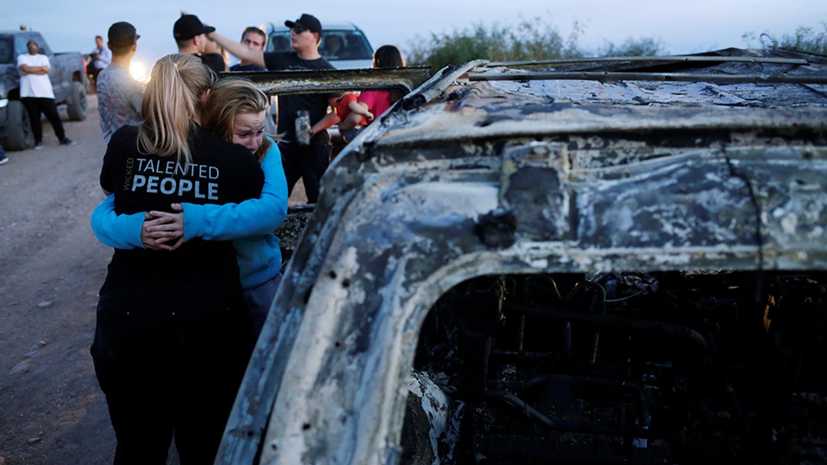 Relatives of slain members of Mexican-American families belonging to Mormon communities react next to the burnt wreckage of a vehicle where some of their relatives died in Sonora state. 