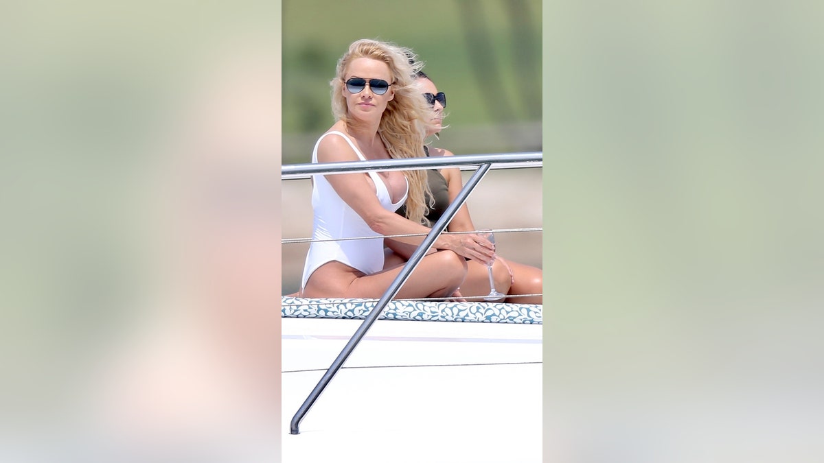 Pamela Anderson poses in a white swimsuit for a photo shoot on the Gold Coast