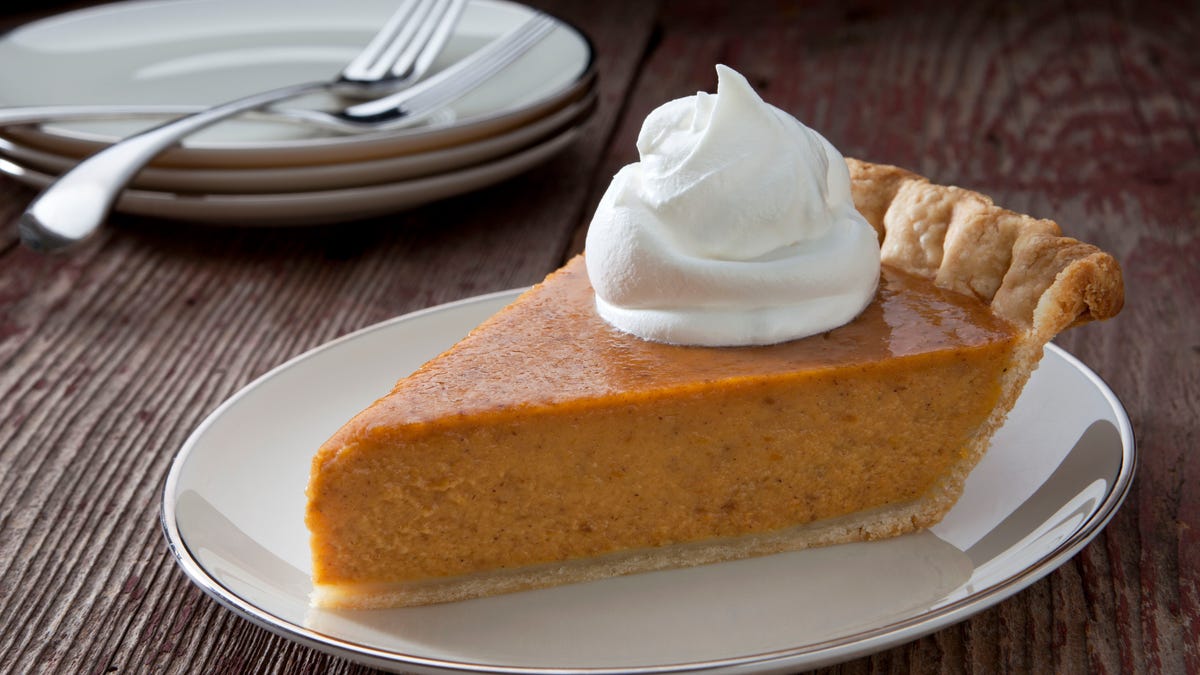 Pumpkin Pie slice with whipped cream on a rustic table.