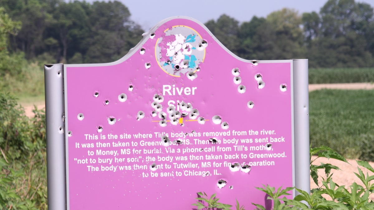 The sight of one of three previous markers at the Emmett Till memorial site. This marker is riddled with bullet holes and later had to be replaced with a marker encased in bulletproof glass. (The Emmett Till Interpretive Center)