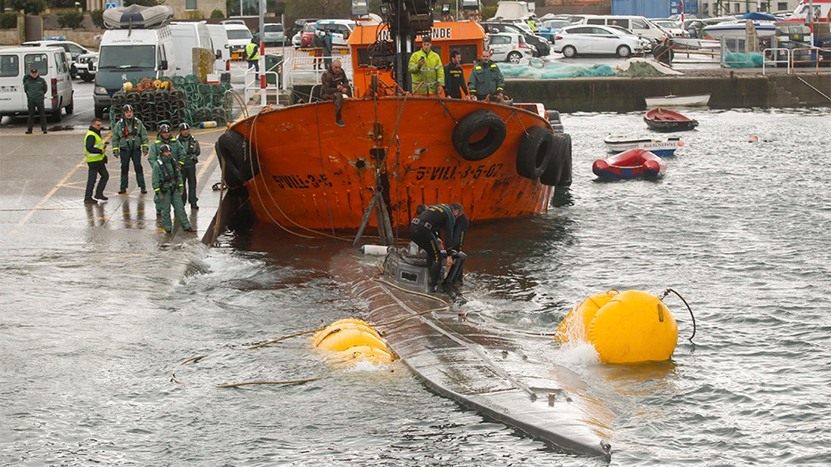 Spanish civil guard tow a sunken submarine believed to be carrying tons of cocaine in Aldan harbor, northwest Spain, on Tuesday. (AP/Europa Press)