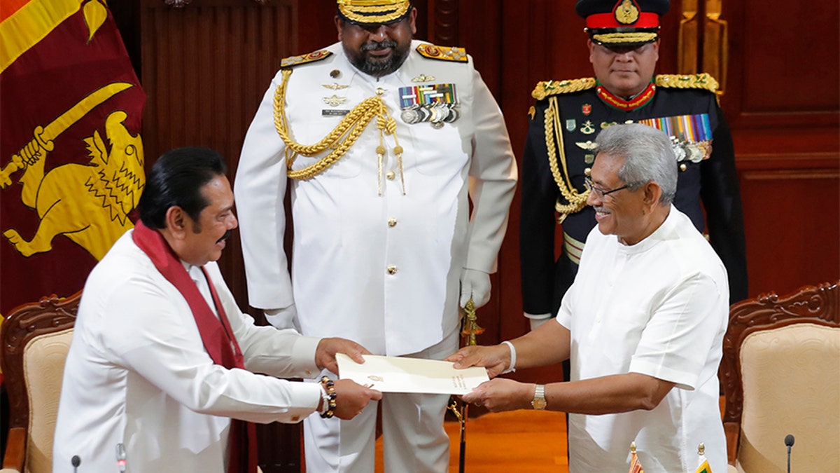 Sri Lanka's President Gotabaya Rajapaksa, right, accepts official documents from his brother Mahinda Rajapaksa after appointing him as prime minister at the presidential secretariat in Colombo, Sri Lanka, on Thursday. (AP)