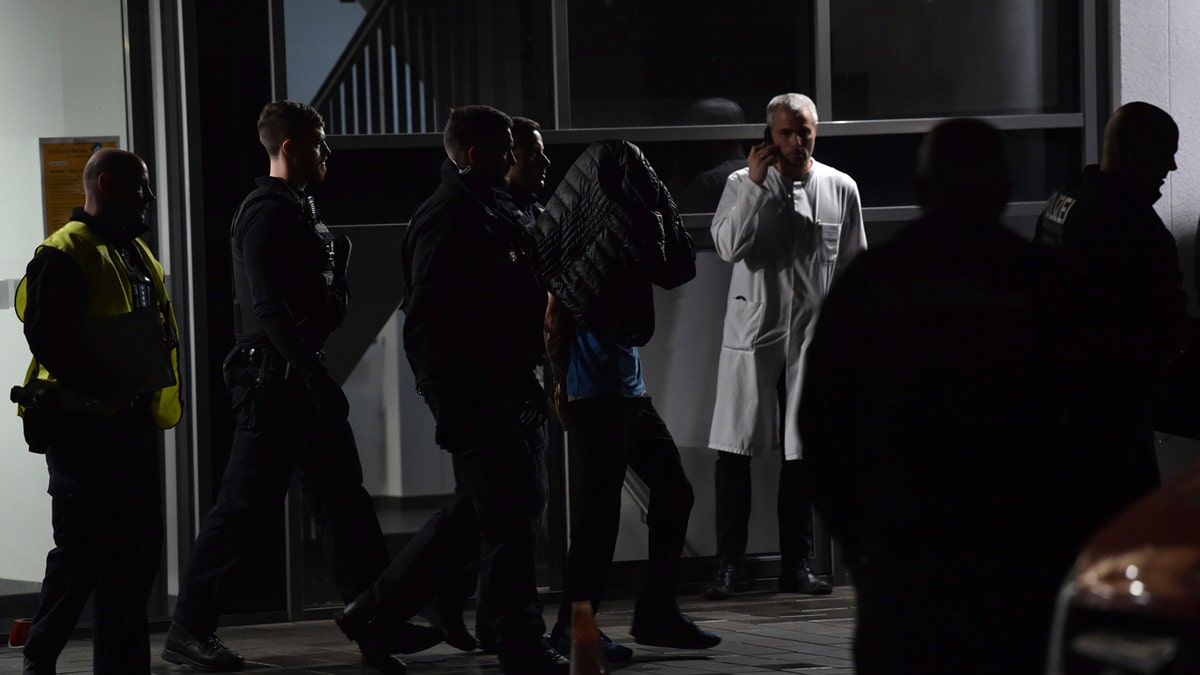 A man is arrested by the police at a hospital in Berlin, Germany after the son of former German Richard von Weizsaecker president was killed while he was giving a lecture. (Paul Zinken/dpa via AP)