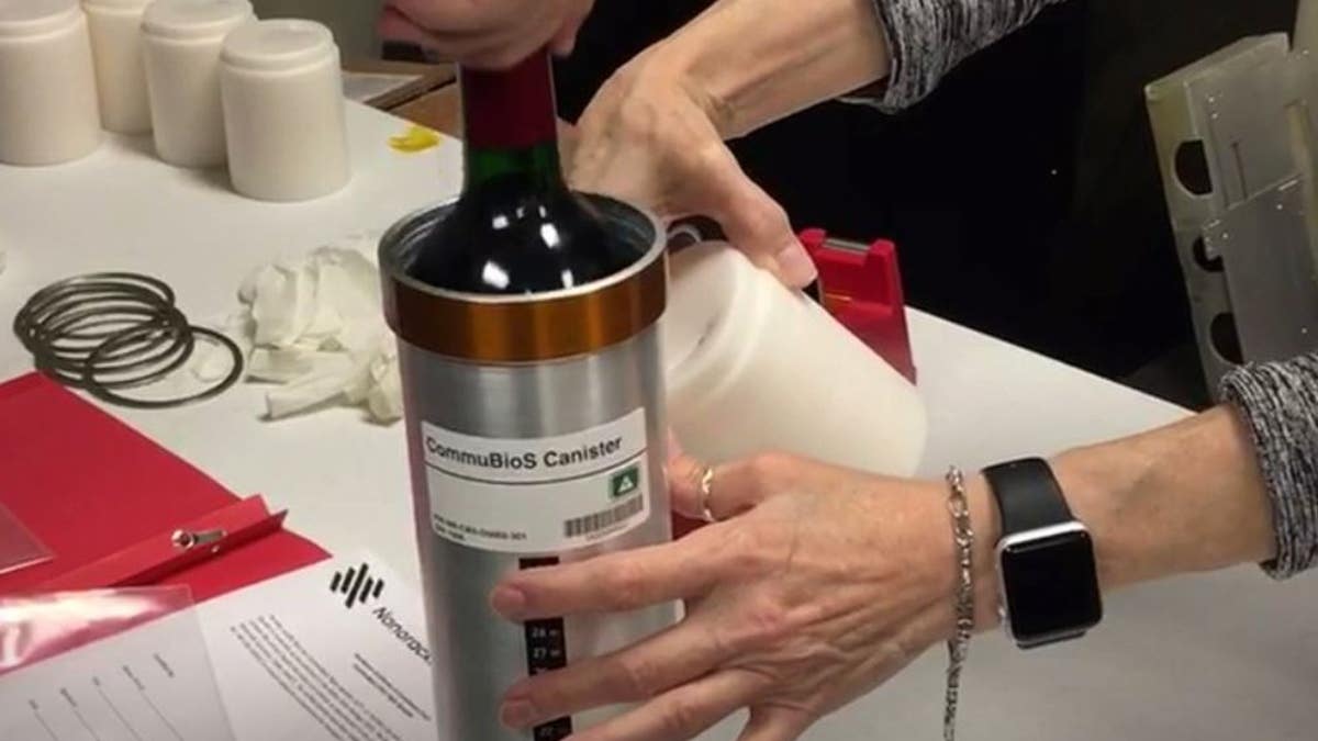 In this Saturday, Nov. 2, 2019 photo provided by Space Cargo Unlimited, researchers with Space Cargo Unlimited prepare bottles of French red wine to be flown aboard a Northrop Grumman capsule from Wallops Island, Va., to the International Space Station.