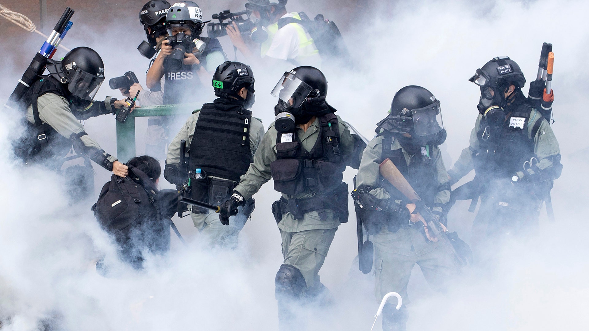 Police move through a cloud of smoke as they detain a protester at the Hong Kong Polytechnic University in Hong Kong, Nov. 18, 2019. 