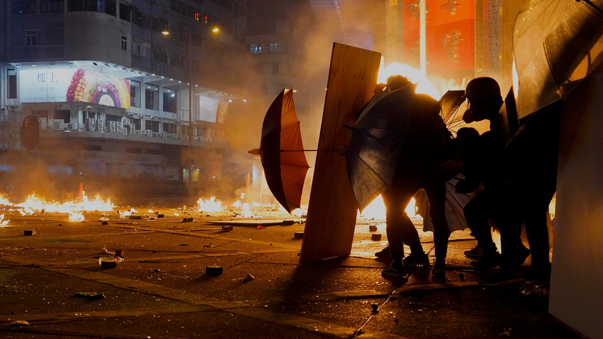 Protestors shield themselves as police fire tear gas in the Kowloon area of Hong Kong, Nov. 18, 2019. 