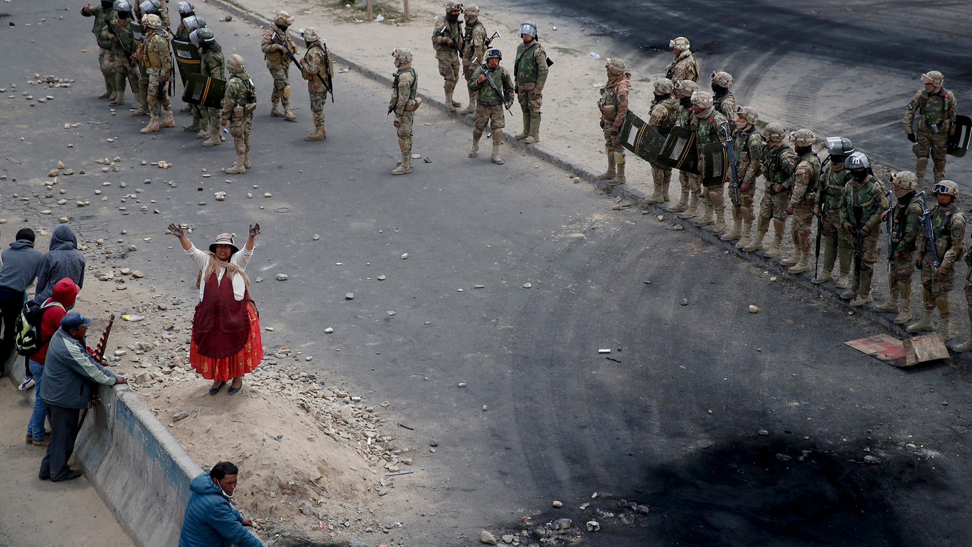 Supporters of former President Evo Morales stand next to soldiers guarding the road leading to the state-own Senkata fuel plant, in El Alto, on the outskirts of La Paz, Bolivia, Nov. 19, 2019.