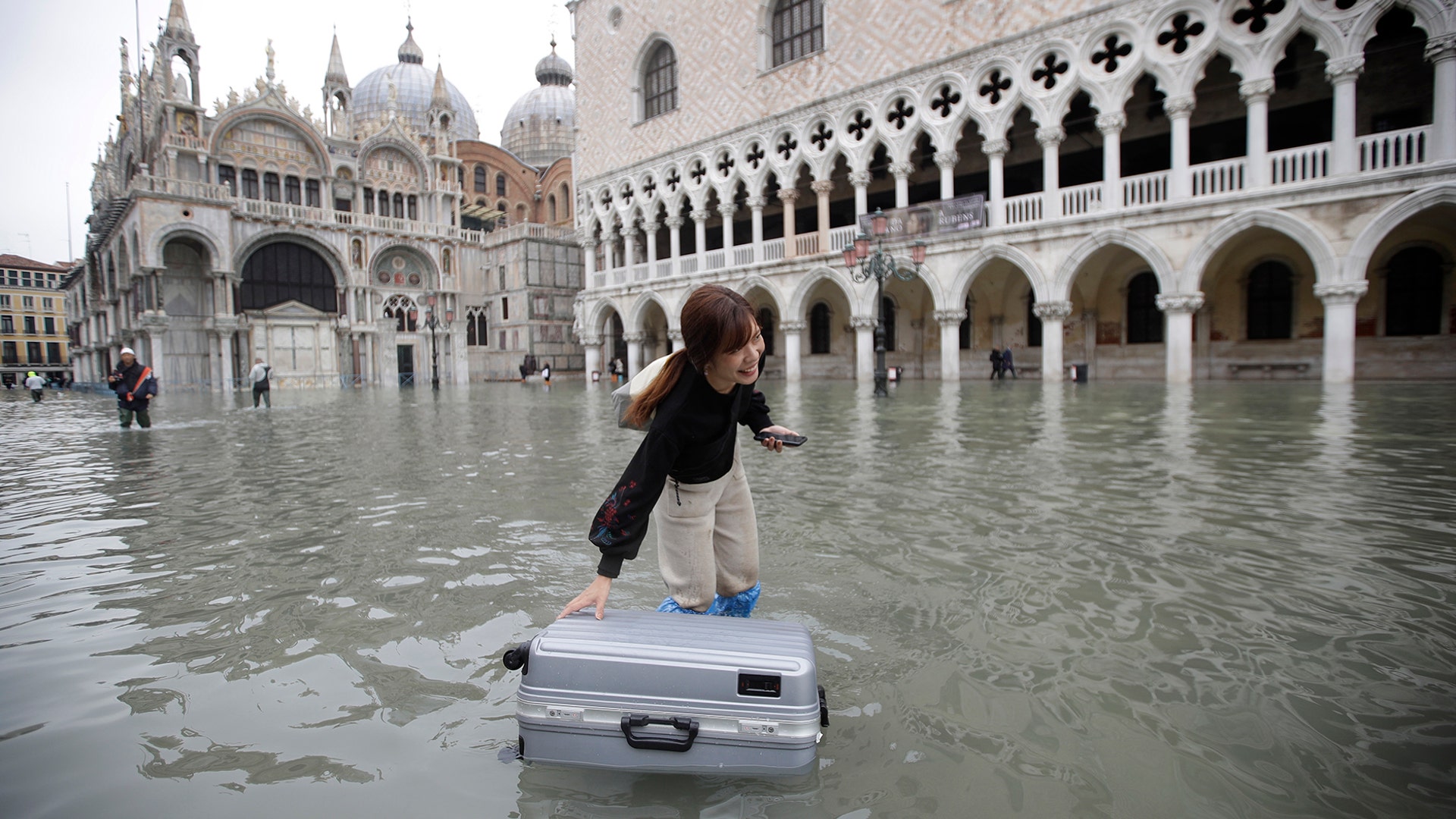 A tourist pushes her floating luggage in a flooded St. Mark's Square, in Venice, Nov. 13, 2019.