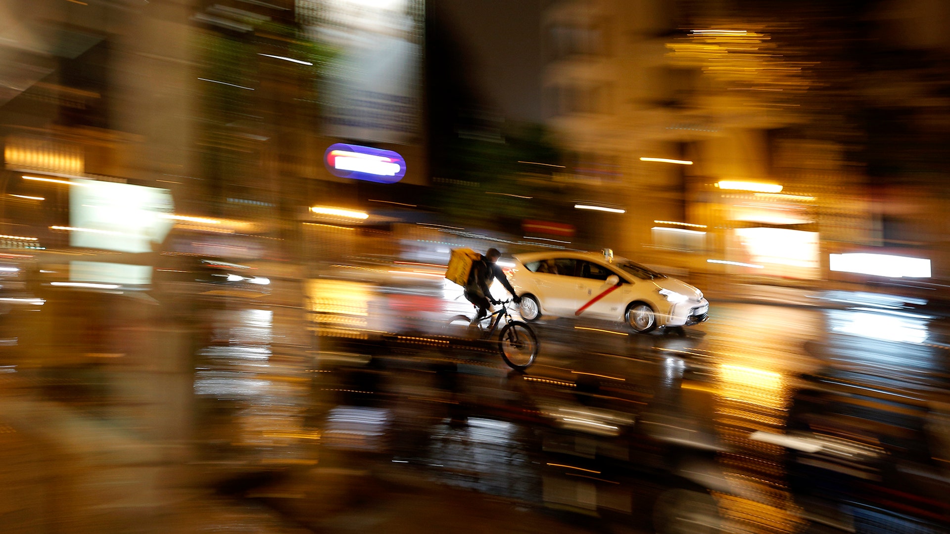 A cyclist rides between cars during an autumn day in Madrid, Spain, Nov. 7, 2019.
