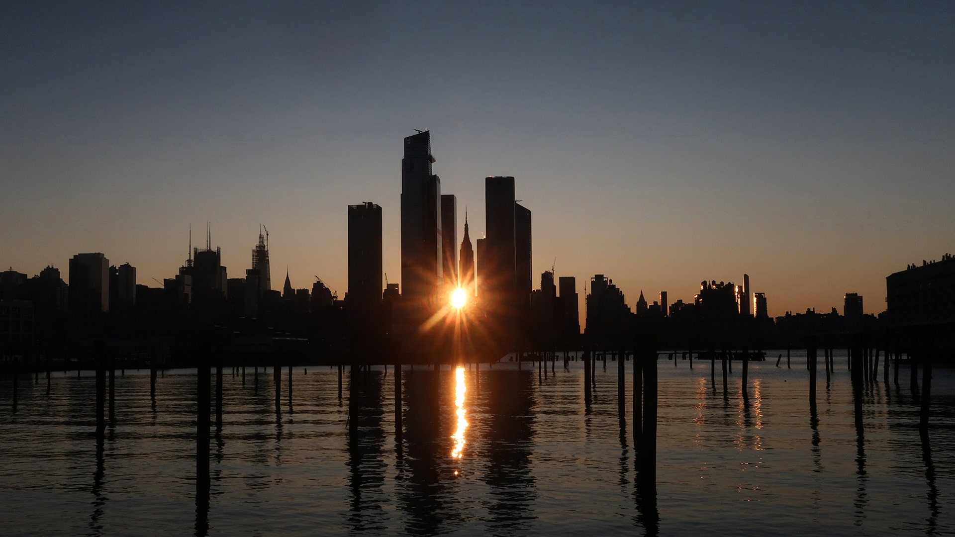 The sun rises behind Hudson Yards and the Empire State Building in New York City, Nov. 3, 2019.
