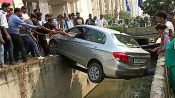 Driver rescued from car balanced on narrow pipe over ditch